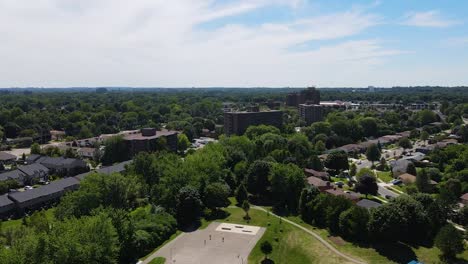 Drone-flying-past-a-basketball-court-on-a-sunny-day-in-London,-Ontario
