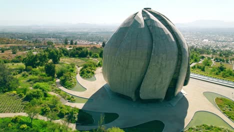 Aerial-orbit-of-the-Bahai-Temple-of-South-America,-wrap-around-architecture,-spring-garden-on-a-sunny-day,-Santiago,-Chile
