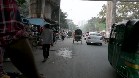 First-person-view-from-a-rickshaw-passenger-seat-as-a-rickshaw-puller,-or-driver,-drives-through-the-congested-streets-of-Dhaka