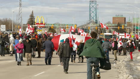 Enorme-Multitud-De-Personas-Caminando-Con-Una-Enorme-Bandera-Canadiense-Bajo-Una-Manifestación-En-Windsor