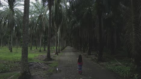 Woman-with-long-hair-walking-in-street-between-palm-trees