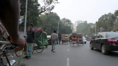 First-person-view-from-a-rickshaw-passenger-seat-as-a-rickshaw-puller,-or-driver,-drives-through-the-traffic-on-the-busy-roads-of-Dhaka