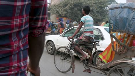 First-person-view-from-a-rickshaw-passenger-seat-as-a-rickshaw-puller,-or-driver,-drives-through-the-congested-roads-of-Dhaka