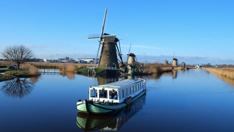 Whisper-boat-slowly-moving-on-a-canal-next-to-the-traditional-windmill-in-Kinderdijk