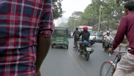 First-person-view-from-a-rickshaw-passenger-seat-as-a-rickshaw-puller,-or-driver,-drives-through-the-traffic-at-the-hectic-roads-of-Dhaka