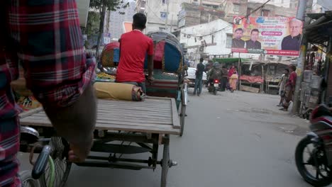 First-person-view-from-a-rickshaw-passenger-seat-as-a-rickshaw-puller,-or-driver,-rides-through-the-roads-of-Dhaka