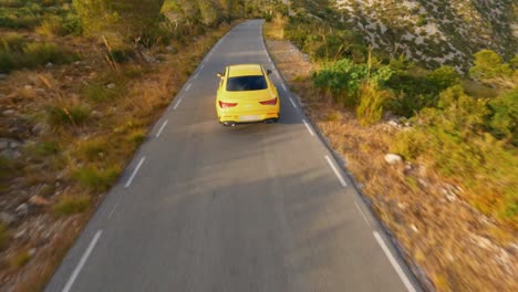 FPV-aerial-following-a-sports-car-traveling-through-the-hills-of-Catalonia-at-sunset