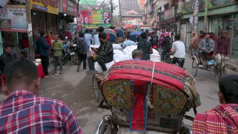 First-person-view-from-a-rickshaw-passenger-seat-as-a-rickshaw-puller,-or-driver,-rides-through-the-busy-roads-of-Dhaka
