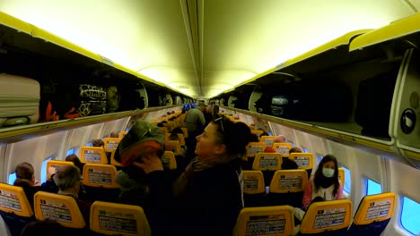Wide-angle-view-inside-airplane-passenger-cabin-corridor-of-Ryanair-flight-before-taking-off---London,-UK