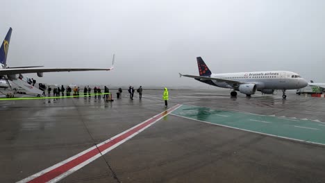 Brussels-Airlines-plane-taxiing-to-airport-gate,-Ryanair-passengers-queueing-for-flight-departure---Brussels-Airport,-Belgium