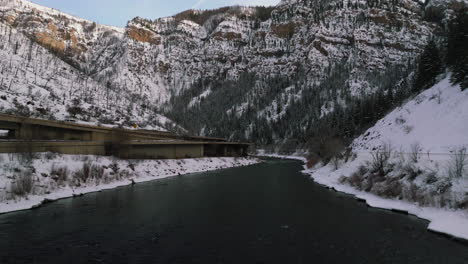 i70-Low-angle-drone-dolley-tilt-shot-of-fast-streaming-Colorado-river-next-to-a-highway-in-the-Glennwood-Canyon