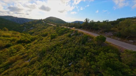 FPV-aerial-following-a-yellow-sports-car-driving-through-the-picturesque-mountain-landscape-of-Catalonia,-Spain-at-sunset