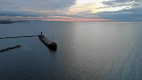 Drone-flying-around-a-large-ship-docked-at-a-harbor-at-sunrise-in-Mississauga