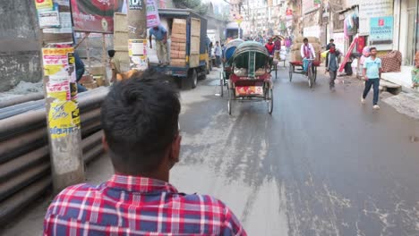 First-person-view-from-a-rickshaw-passenger-seat-as-a-rickshaw-puller,-or-driver,-rides-through-the-streets-of-Dhaka