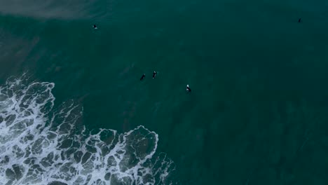 Aerial-view-of-surfers-sitting-in-the-water