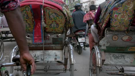 First-person-view-from-a-rickshaw-passenger-seat-as-a-rickshaw-puller,-or-driver,-drives-through-the-hectic-roads-of-Dhaka