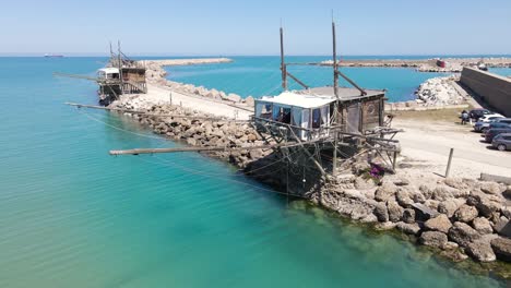 Wide-angle-orbiting-drone-shot-of-an-old-wooden-structure-called-a-"Trabucco"-that-is-an-ancient-method-of-fishing-using-this-platform-with-a-large-net-for-fishing