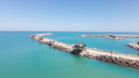 Wide-angle-orbiting-drone-shot-of-an-old-wooden-structure-called-a-"Trabucco"-that-is-an-ancient-method-of-fishing-using-this-platform-with-a-large-net-for-fishing