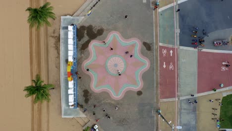 Bird's-eye-top-view-shot-of-the-center-plaza-at-the-touristic-Tambaú-beach-boardwalk-in-the-tropical-beach-capital-city-of-Joao-Pessoa,-Paraiba,-Brazil-with-people-gathering-for-pictures-at-the-sign