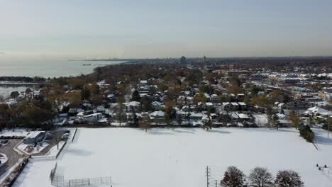Flying-along-the-coastline-of-a-frozen-Lake-Ontario-covered-in-snow-in-Mississauga