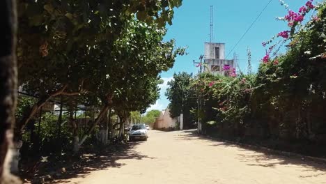 Slow-motion-shot-moving-down-a-small-cobblestone-road-surrounded-by-tropical-plants-in-the-small-town-of-Canguaretama-near-Tibau-do-Sul-and-Natal-in-Rio-Grande-do-Norte,-Brazil-on-a-summer-day