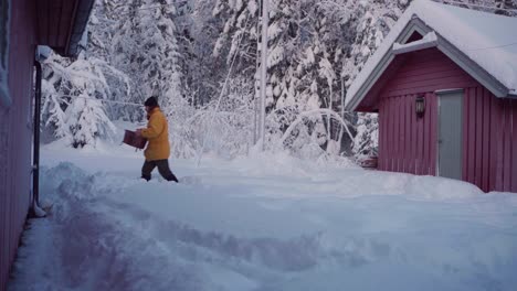 Man-Walking-On-Snowy-Landscape-Outside-Cabin-In-Winter