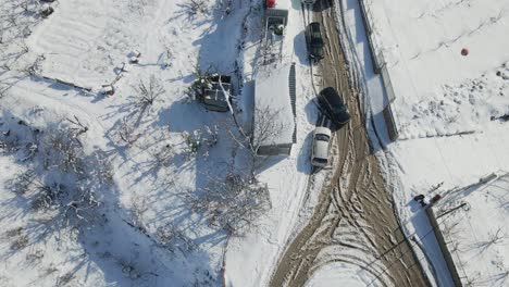 Drone-top-view-of-cars-and-trucks-driving-on-vineyard-farm-dirt-road-with-snow,-Israel