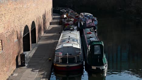 A-single-lady-walking-past-some-boats-on-the-Regents-Canal,-London,-United-Kingdom