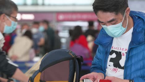 A-flight-travel-passenger-manages-his-airline-boarding-pass-after-checking-in-at-the-airline-desk-counter-at-Hong-Kong-International-Airport