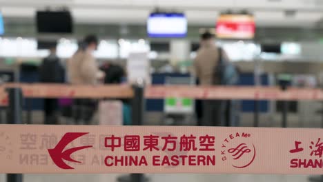 Das-Logo-Der-Chinesischen-Fluggesellschaft-China-Eastern-Airlines-Ist-Auf-Einem-Warteschlangenband-Im-Vordergrund-An-Einem-Check-in-Schalter-Am-Internationalen-Flughafen-Chek-Lap-Kok-In-Hongkong-Zu-Sehen