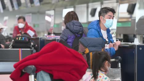 Travel-flight-passengers-queue-in-line-to-check-in-at-the-Air-China-airline-desk-counter-at-Hong-Kong's-Chek-Lap-Kok-International-Airport