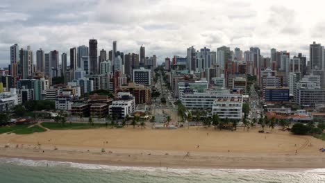 Aerial-drone-shot-of-the-famous-tourist-destination-Tambaú-beach-in-the-tropical-capital-city-of-Joao-Pessoa-in-Paraiba,-Brazil-with-golden-sand-surrounded-by-large-buildings-and-skyscrapers