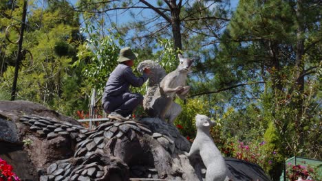Vietnamese-Man-Painting-Giant-Clay-Sculpture-Of-Squirrel-At-The-Clay-Tunnel-In-Dalat,-Vietnam