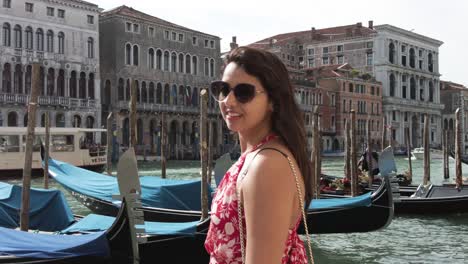 Mujer-Turista-Irradia-Alegría-Mientras-Posa-Y-Mira-La-Cámara-Contra-El-Telón-De-Fondo-De-La-Impresionante-Venecia-En-Italia
