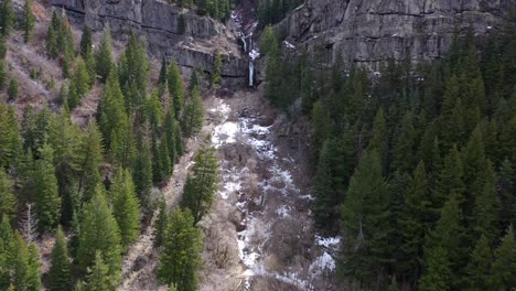 Dramatische-Schatten-über-Einem-Gefrorenen-Wasserfall,-Umgeben-Von-Immergrünen-Bäumen