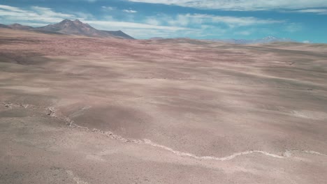 Dron-Panorámico-En-El-Cielo-Sobre-El-Desierto-Chileno-Con-Un-Volcán-En-El-Fondo