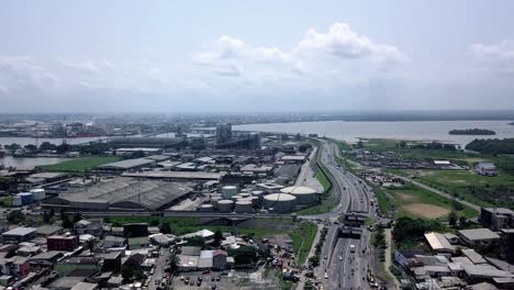 Vista-Aérea-De-Una-Zona-Industrial-En-La-Soleada-Ciudad-De-Douala,-Camerún---Seguimiento,-Disparo-De-Drones