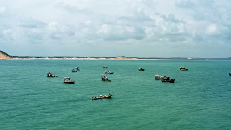 Luftdrohnen-Landschaftsaufnahme-Einer-Reihe-Kleiner-Fischerboote,-Die-In-Der-Nähe-Des-Cacimba-Strands-Mit-Sanddünen-Im-Hintergrund-In-Der-Berühmten-Strandstadt-Baia-Formosa-In-Rio-Grande-Do-Norte,-Brasilien,-Angedockt-Sind