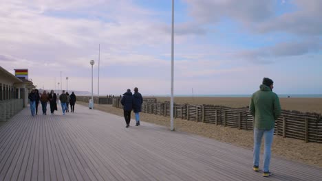 Locals-And-Tourists-Walking-In-The-Les-Planches-Promenade,-Popular-Wooden-Promenade-Beside-The-Deauville-Beach-In-France