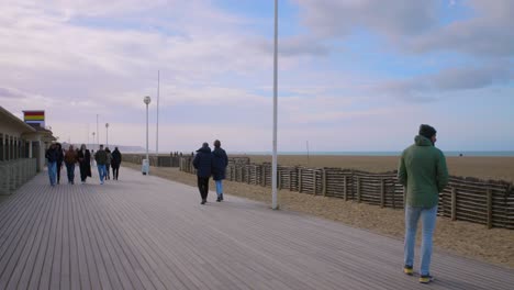 Lugareños-Y-Turistas-Caminando-En-El-Paseo-Marítimo-De-Les-Planches,-Popular-Paseo-Marítimo-De-Madera-Junto-A-La-Playa-De-Deauville-En-Francia