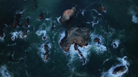 Top-down-aerial-view-of-a-rock-filled-shoreline-off-the-coast-of-California