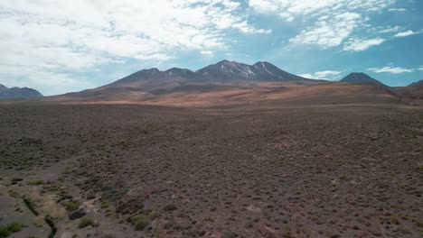 Drohnenaufnahmen-Zu-Einem-Vulkan-In-Der-Chilenischen-Wüste,-Vorbei-An-Der-Trockenen-Vegetation-Auf-Dem-Boden