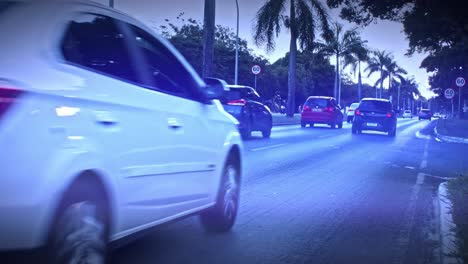 Clip-from-the-center-lane-as-cars-travel-along-the-road-at-dusk-just-after-light-rain
