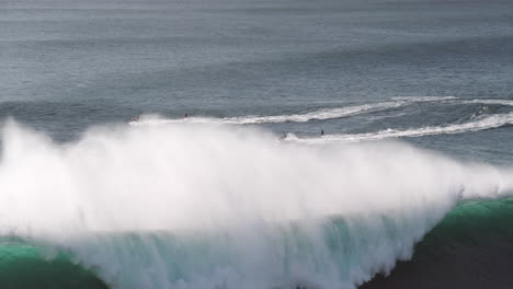 Jet-ski-drivers-pulling-surfers-onto-big-wave-in-Nazare,-Portugal,-slow-motion