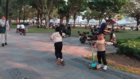 Kids-riding-scooters-and-playing-in-Linjiang-Linear-Park,-Guangzhou,-China