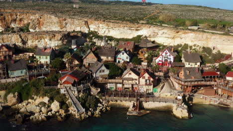 Rustic-Huts-In-Popeye-Village-In-Mellieha,-Malta---aerial-drone-shot