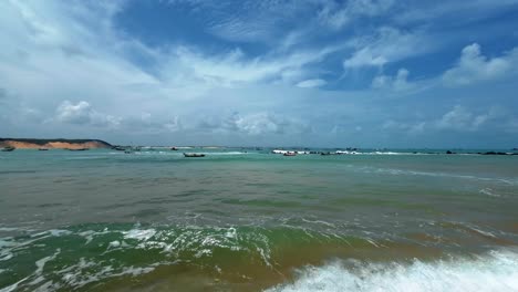 Tilt-up-action-camera-shot-of-the-beautiful-tropical-Cacimba-beach-in-the-famous-coastal-surf-town-of-Baia-Formosa-in-Rio-Grande-do-Norte,-Brazil-with-calm-waves-and-small-fishing-boats-docked