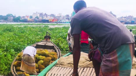 A-trawler-engine-boat-loaded-with-jackfruit-is-seen-near-Dhaka-city,-reflecting-the-wholesale-fruit-trade-and-food-supply-concept