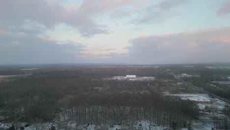 Aerial-Shot-of-Winter-Sunset-with-bare-trees-and-light-dusting-of-snow