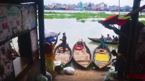 Los-Pasajeros-Con-Sacos-En-La-Cabeza-Cruzan-El-Río-Buriganga-A-Través-De-Un-Embarcadero-En-Dhaka,-Bangladesh.